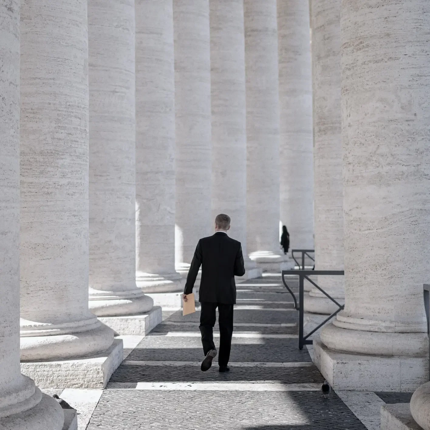 Man in a suit walking between columns2
